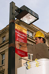 Worker installs banner on light pole
