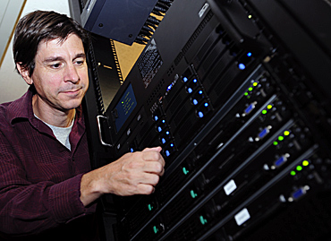 Jim Cochran works with computer equipment that will help him coordinate American analysis of data from the Large Hadron Collider.