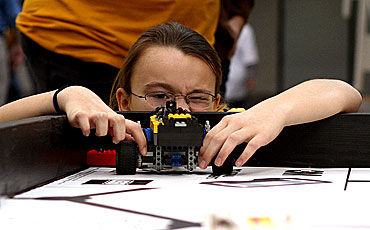 A FIRST LEGO League participant lines up her team's robot during table-top competition.